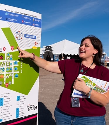A BBQ Austin committee volunteer pointing at a map of the Rodeo Austin grounds.