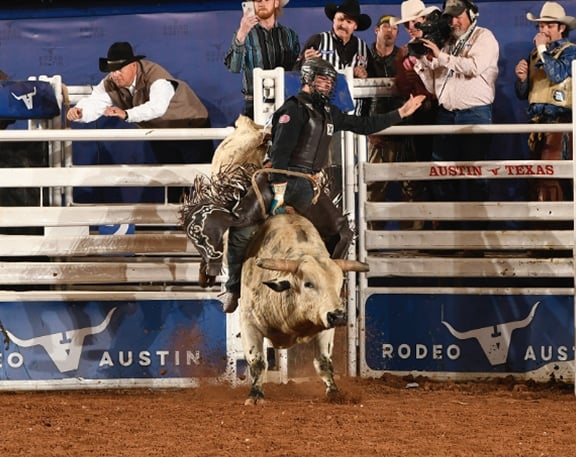 bull rider on bucking bull in arena