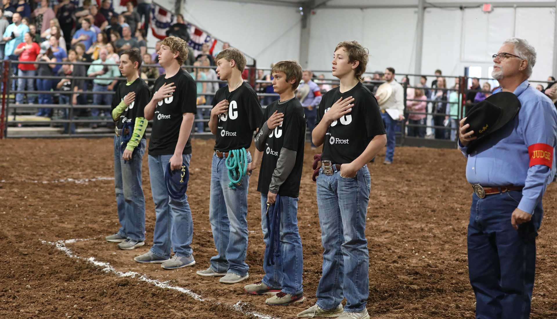 Rodeo Austin Calf Scramble participants with hands on heart during the National Anthem