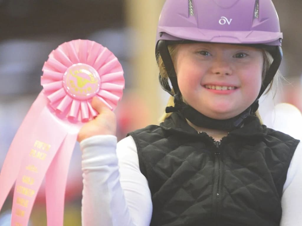 young girl holding a rodeo award ribbon