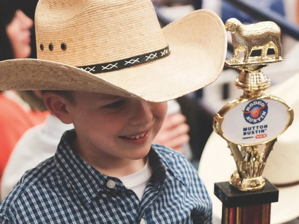 young boy holding a rodeo trophy