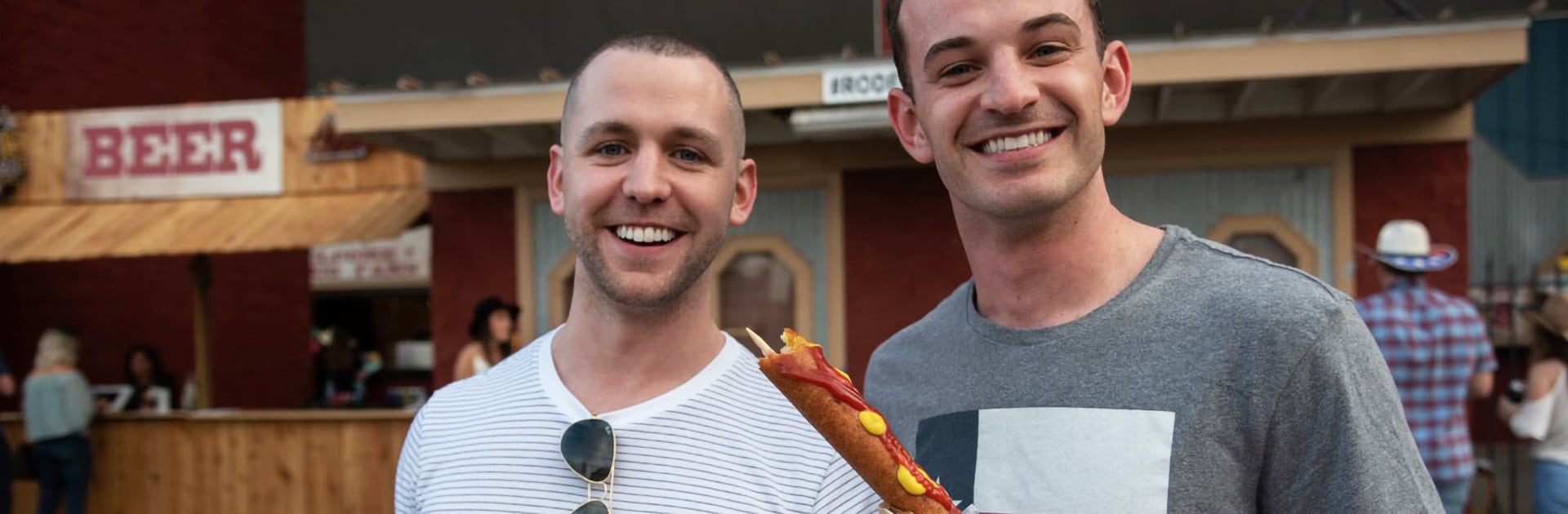 two men enjoying corn dogs
