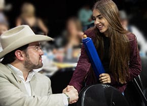 A man in a cowboy hat shaking hands with a young woman.